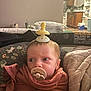 baby, pacifier, blanket, indoor, child, face, expression, kitchen, furniture, wrapped, headwear, comfort, young, person, couch, soft, household, infant, warm, cute
