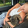 animal, car_interior, casual_clothing, cat, child, comfort, daylight, friendship, girl, grass, gray_pants, nature, pet, relaxation, seat, sleeping, tabby_cat, trees, white_tank_top, window