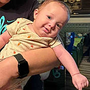 Solomon is registered to the contest to win money with this photo: arm, arm_outstretched, baby, casual, child, fruit_print, furniture, happy, head_tilt, holding, indoor, infant, nike_shirt, onesie, person, portrait, radio, skin, smile, watch