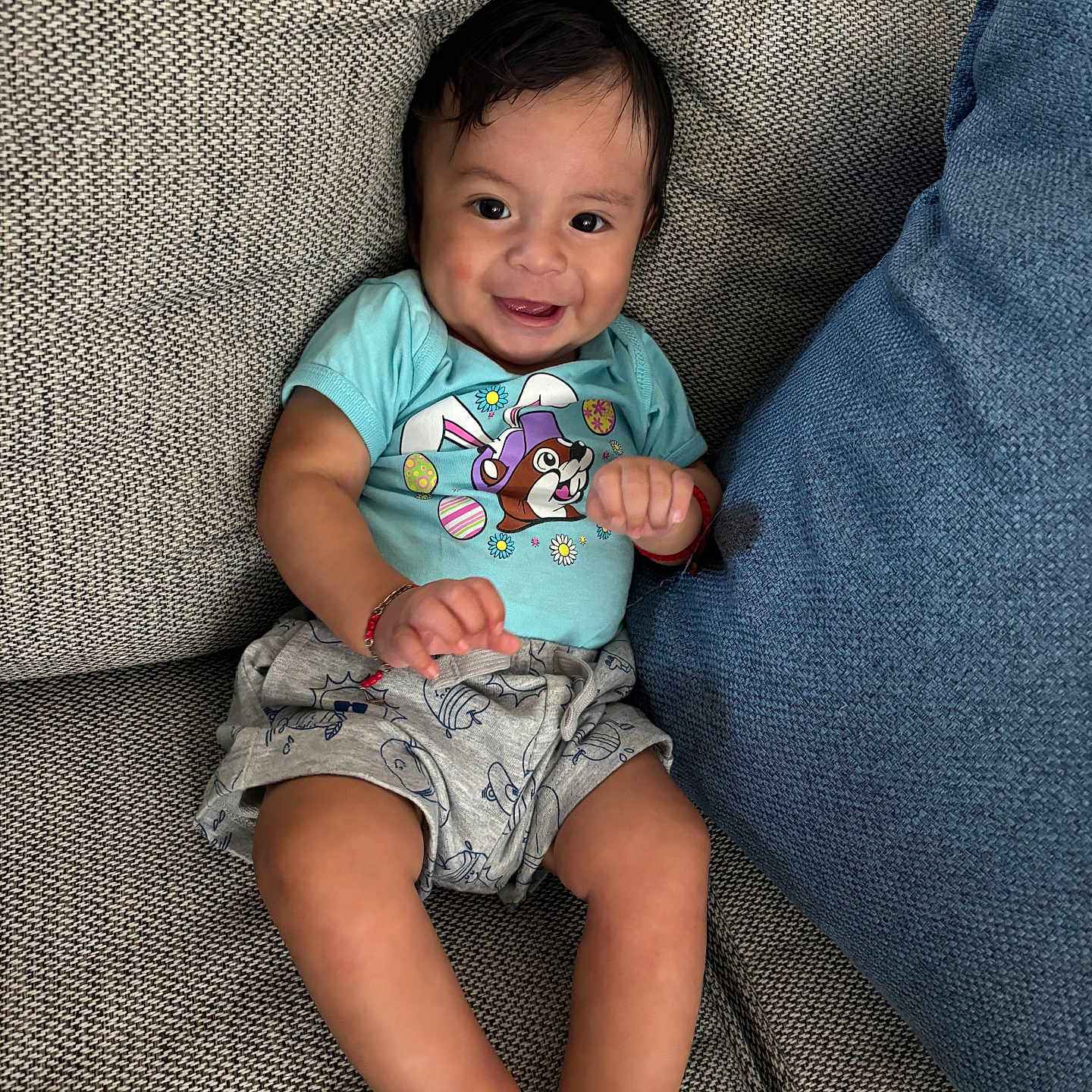 Anthony álvarez joined the competition — help win amazing prizes! baby, child, smiling, couch, blue_cushion, shorts, tshirt, cartoon_print, indoor, happy, infant, sitting, cute, skin, face, legs, hands, furniture, relaxed, comfortable