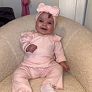 Maya is registered to the contest to win money with this photo: baby, baby_outfit, child, comfortable, cozy_chair, cute, furniture, happy, headband, headwear, indoor, infant, person, pink_clothing, portrait, sitting, smiling, sock, soft_texture, young_child