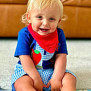 Peyton joined the competition — help win amazing prizes! toddler, child, smiling, blonde_hair, blue_eyes, red_bandana, blue_shirt, checkered_shorts, sitting, indoors, carpet, play_mat, happy, cute, portrait, person, young_child, couch, home, casual_clothing