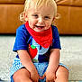 toddler, child, smiling, blonde_hair, blue_eyes, red_bandana, blue_shirt, checkered_shorts, sitting, indoors, carpet, play_mat, happy, cute, portrait, person, young_child, couch, home, casual_clothing