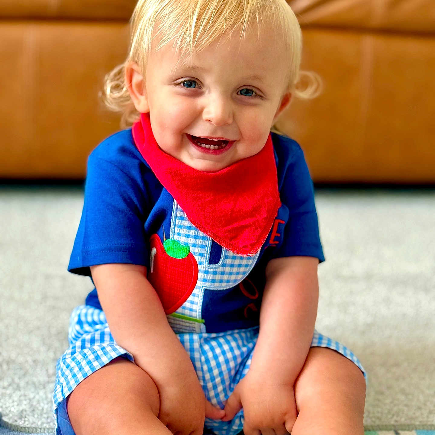 Peyton joined the competition — help win amazing prizes! blonde_hair, blue_eyes, blue_shirt, carpet, casual_clothing, checkered_shorts, child, couch, cute, happy, home, indoors, person, play_mat, portrait, red_bandana, sitting, smiling, toddler, young_child