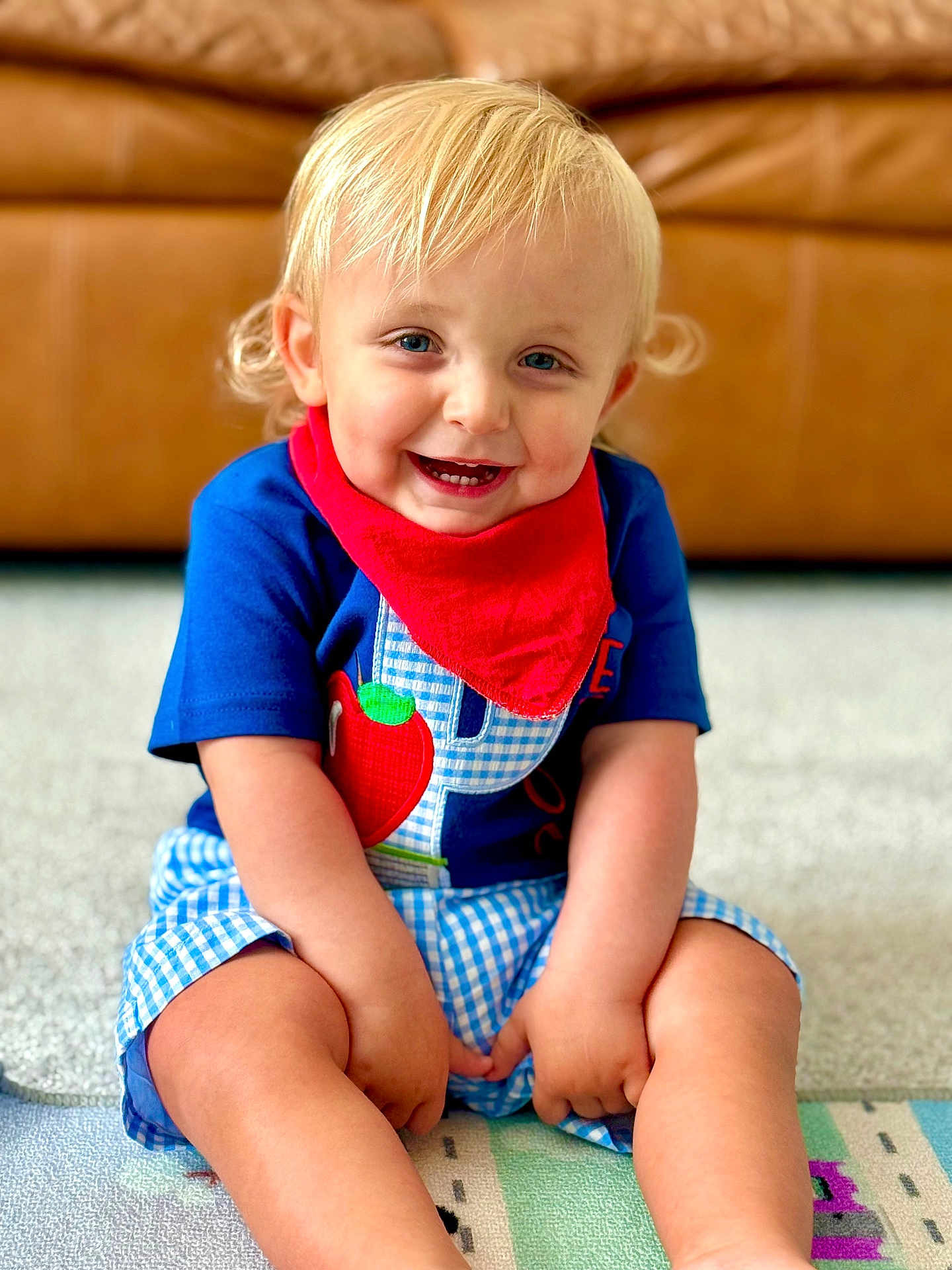 Peyton joined the competition — help win amazing prizes! toddler, child, smiling, blonde_hair, blue_eyes, red_bandana, blue_shirt, checkered_shorts, sitting, indoors, carpet, play_mat, happy, cute, portrait, person, young_child, couch, home, casual_clothing