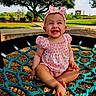 Zoey is registered to the contest to win money with this photo: baby, child, cute, girl, grass, happy, headband, infant, outdoor, park, pink_clothing, playground, rope, seated, smiling, sunny, swing, toothy_smile, tree, wood_chips