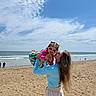 Alayah joined the competition — help win amazing prizes! beach, casual, child, clouds, colorful_clothing, family, fun, happy, holding, ocean, outdoor, playing, sand, sky, smile, summer, sunglasses, sunny, vacation, woman