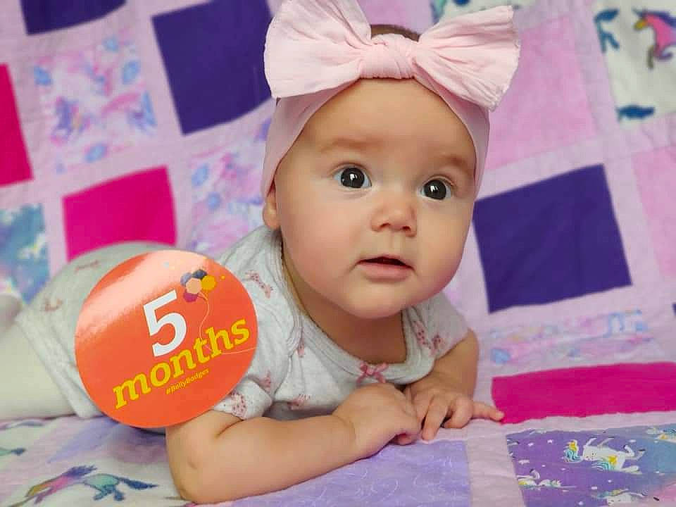 Lyra is registered to the contest to win money with this photo: baby, baby_playing_with_toys, baby_products, baby_toddler_clothing, cheek, child, fashion_accessory, flooring, fun, happy, headwear, linens, magenta, party_supply, person, pink, play, portrait_photography, room, skin