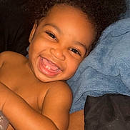 Trevon joined the competition — help win amazing prizes! child, toddler, smiling, happy, face, baby, curly_hair, blanket, blue_blanket, skin, close_up, portrait, lying_down, cute, joyful, indoor, person, expression, young_child, bare_shoulders