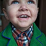 child, toddler, blue_eyes, smiling, green_jacket, plaid_shirt, face, portrait, happy, cute, young, person, apparel, indoors, closeup, buttoned_shirt, childhood, fashion, expression, looking_up