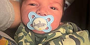 Everett joined the competition — help win amazing prizes! baby, pacifier, camo_pattern, blanket, infant, face, person, sleepy, closeup, cute, child, newborn, soft, comfort, indoor, clothing, human, young, resting, toddler