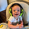 toddler, child, headphones, high_chair, smiling, food, messy_face, indoor, kitchen, snack, tray, white_shirt, seat, baby, happy, person, cute, noise_cancelling_headphones, bright_colors, infant