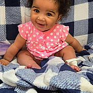 Nala Ann is registered to the contest to win money with this photo: baby, child, infant, smiling, pink_clothing, polka_dot, curly_hair, blanket, checkered_pattern, blue_and_white, sitting, cute, happy, indoors, portrait, young_child, cozy, soft_texture, face, person