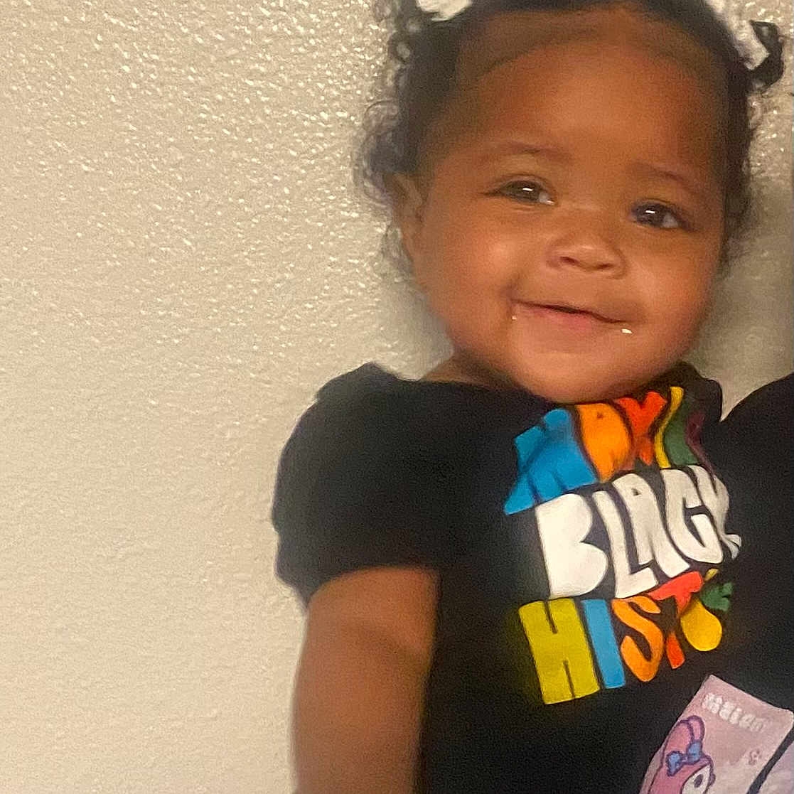 Jordan Lanae Jream joined the competition — help win amazing prizes! black_history, bows, casual_clothing, child, colorful_text, cute, face, happy, indoor, jeans, person, pigtails, portrait, short_sleeves, smiling, standing, toddler, tshirt, wall, young_child