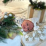 baby, blanket, celebration, christmas_decor, cute, decorations, face, festive, gift_box, headband, holiday, holiday_season, indoor, infant, person, pine_cone, smile, soft_texture, toddler, white_clothing