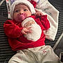 baby, blanket, child, christmas, clothing, cozy, cute, face, festive, holiday, indoors, infant, lying_down, pacifier, patterned_pants, person, red_sweater, santa_hat, socks, soft_texture
