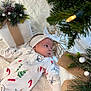Nova is registered to the contest to win money with this photo: baby, infant, holiday, christmas, pajamas, blanket, decoration, pinecones, pine_branches, gift_wrap, headband, soft_texture, festive, lying_down, indoors, cute, winter, seasonal, sleepwear, child