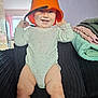 baby, child, smiling, orange_bucket, onesie, couch, indoor, towels, happy, playful, infant, furniture, legs, face, headwear, room, light, casual, cute, funny