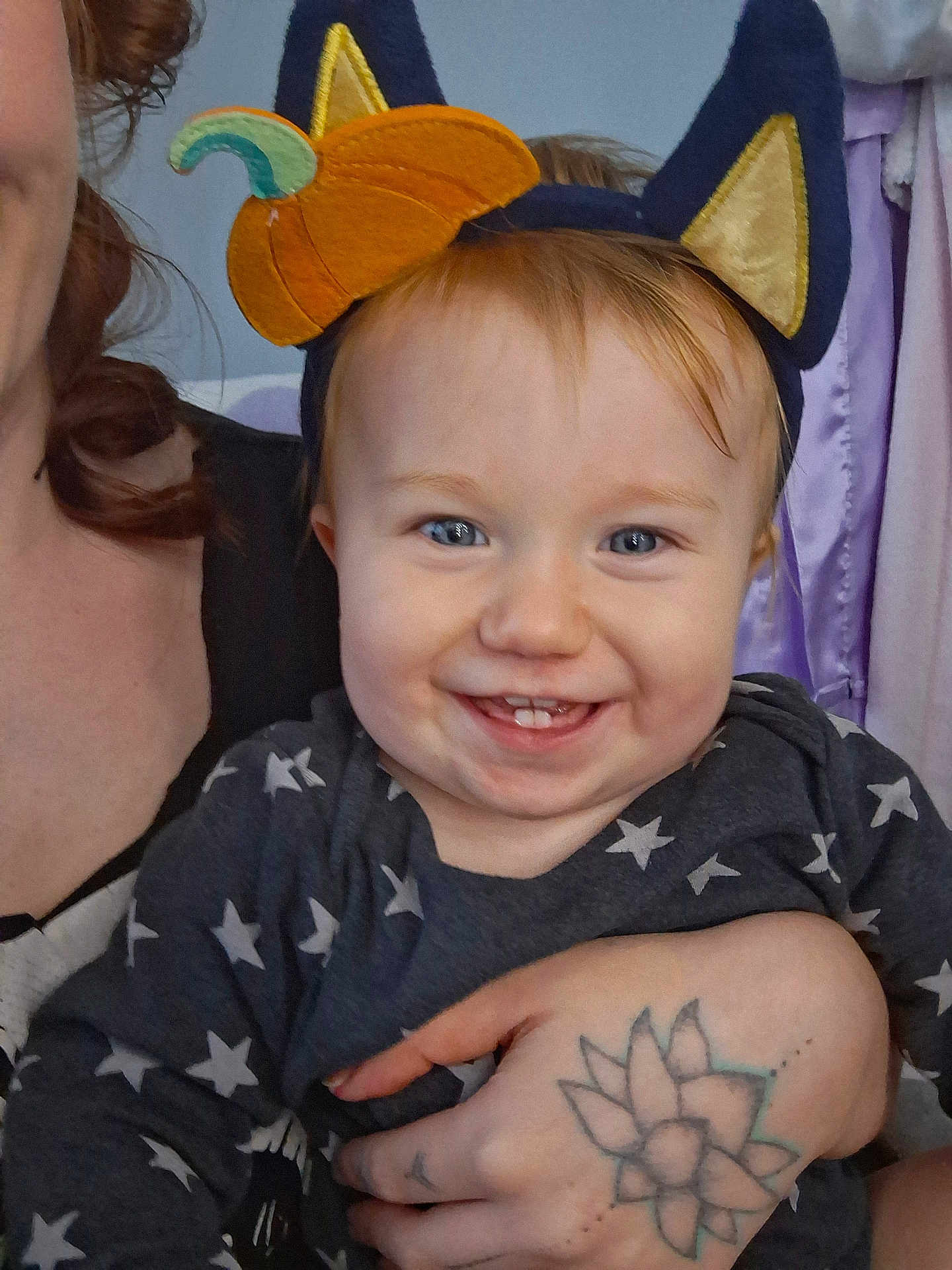 Arlo joined the competition — help win amazing prizes! baby, child, smile, headband, cat_ears, pumpkin, tattoo, hand, person, face, blue_eyes, clothing, stars_pattern, indoor, curtains, happy, holding, portrait, cute, adult