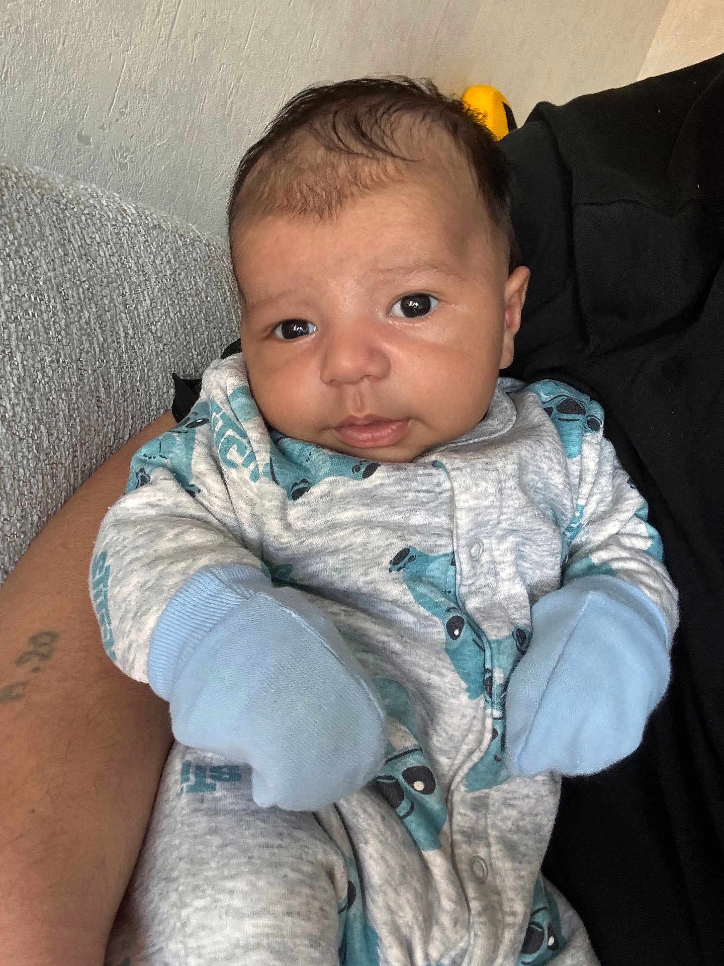 Noah participe au concours pour gagner de l'argent avec cette photo : baby, infant, onesie, mittens, person, portrait, cute, child, clothing, indoor, hand, tattoo, face, expression, sitting, comfort, skin, adult_arm, cozy, gaze