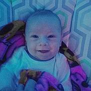 Bryson is registered to the contest to win money with this photo: baby, smiling, blanket, patterned_background, soft_lighting, infant, child, portrait, indoors, cute, happy, cozy, colorful, fabric, wrapped, head, face, young_child, lying_down, blue_tone