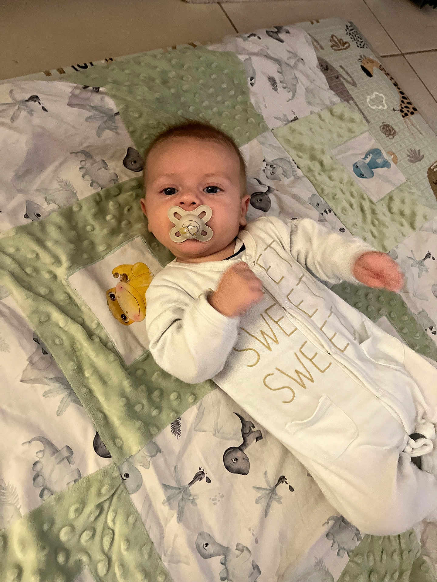 Ethan a rejoint le concours — aidez-le/la à gagner de superbes lots ! baby, pacifier, blanket, onesie, infant, child, indoor, floor, animal_print, comfort, cozy, cute, sleepwear, toddler, motion_blur, portrait, lying_down, soft_texture, baby_girl, baby_boy