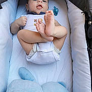 Ethan participe au concours pour gagner de l'argent avec cette photo : baby, infant, stroller, cushion, pacifier, clothing, feet, face, person, child, playful, indoors, blanket, comfort, cute, soft_toy, blue, white, resting, young