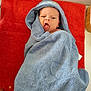 baby, child, towel, blue_towel, red_towel, hood, face, expression, mouth_open, eyes, skin, person, infant, lying_down, indoor, soft_texture, cute, cozy, wrapped, hand