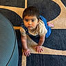 Tiara Chowdary is registered to the contest to win money with this photo: toddler, child, crawling, carpet, patterned_carpet, overalls, beige_shirt, indoor, floor, ottoman, curious, serious_expression, young_child, hands, feet, brown_hair, face, person, home, casual_clothing