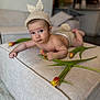 baby, infant, knitted_hat, bunny_ears, tulips, flower, ottoman, beige, indoor, living_room, cute, child, portrait, soft_lighting, couch, home_decor, laying_down, curious, expression, hand