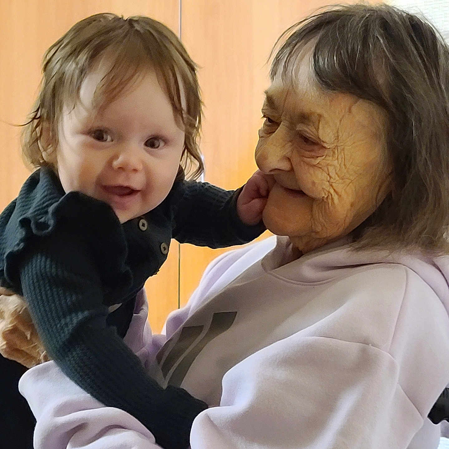 Blaire is registered to the contest to win money with this photo: baby, child, clothing, elderly_woman, face, family, hair, hands, happy, holding, indoor, interaction, love, person, portrait, skin, smile, sweatshirt, warmth, wrinkles