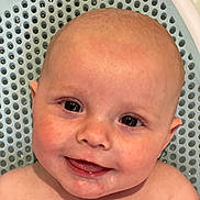 Mateo is registered to the contest to win money with this photo: baby, child, smile, face, head, skin, water_droplets, close_up, eyes, tooth, happy, infant, bath_time, background, texture, blue, expression, person, cute, portrait