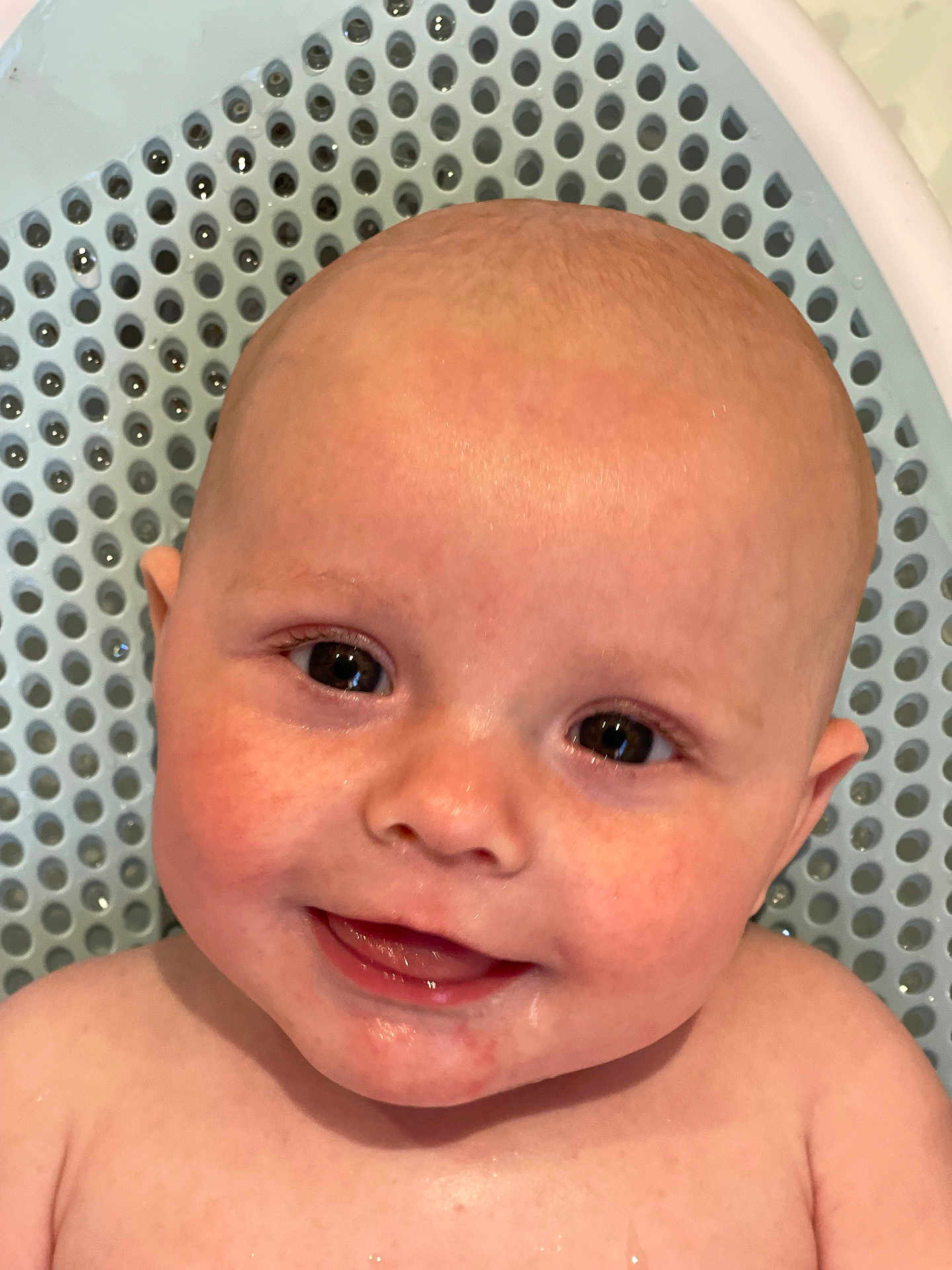 Mateo is registered to the contest to win money with this photo: baby, child, smile, face, head, skin, water_droplets, close_up, eyes, tooth, happy, infant, bath_time, background, texture, blue, expression, person, cute, portrait