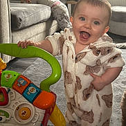 Toni-Louise joined the competition — help win amazing prizes! baby, child, toy, walker, onesie, animal_print, smiling, indoor, carpet, sofa, furniture, happy, person, play, toddler, couch, floor, hand, face, background