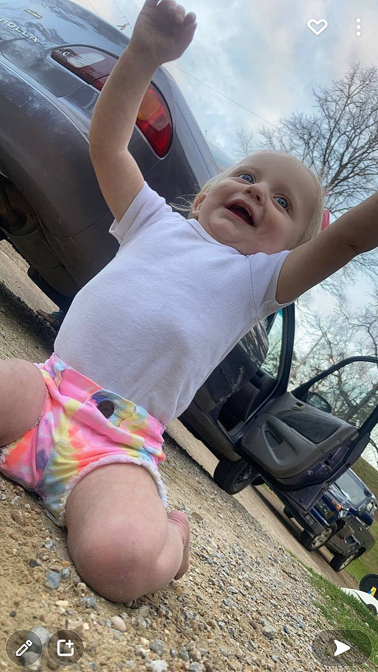 Kendal joined the competition — help win amazing prizes! automotive_exterior, automotive_tire, car, finger, fun, gesture, grass, happy, leisure, person, pink, plant, public_space, shoulder, sky, smile, tire, tree, vehicle_door, vertebrate