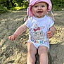 baby, child, pink_hat, onesie, bunny_print, smiling, sand, outdoor, nature, greenery, sunlight, happy, cute, sitting, young_child, summer, playful, portrait, headwear, barefoot