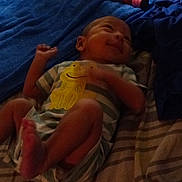 Josiah is registered to the contest to win money with this photo: baby, bed, bedroom, blanket, blue_blanket, clothing, cozy, face, feet, indoor, infant, lipstick, lying_down, newborn, onesie, portrait, rumpled_clothes, sleeping, smiling, yellow_character