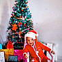 Mateo a rejoint le concours — aidez-le/la à gagner de superbes lots ! celebration, chair, child, christmas_tree, decorations, festive, gift_bags, happy, holiday, home, indoor, ornaments, pointing, portrait, presents, red_outfit, santa_hat, seasonal, smiling, toddler