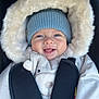 baby, infant, child, smiling, beanie, fur_hood, winter_coat, car_seat, harness, bundled_up, blue_eyes, rosy_cheeks, closeup, portrait, cozy, cute, tongue_out, soft_lighting, plush, warm_tones