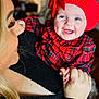 Honey is registered to the contest to win money with this photo: baby, child, smile, red_hat, red_bow, red_plaid_clothing, adult, blonde_hair, black_sweater, indoor, holding, happy, portrait, face, hand, cozy, love, family, cute, expression