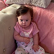 Yaren is registered to the contest to win money with this photo: baby, child, pink_clothing, sitting, couch, pillow, blanket, rainbow_pattern, indoors, cute, infant, face, expression, soft_furniture, home, comfortable, person, legs, feet, hair