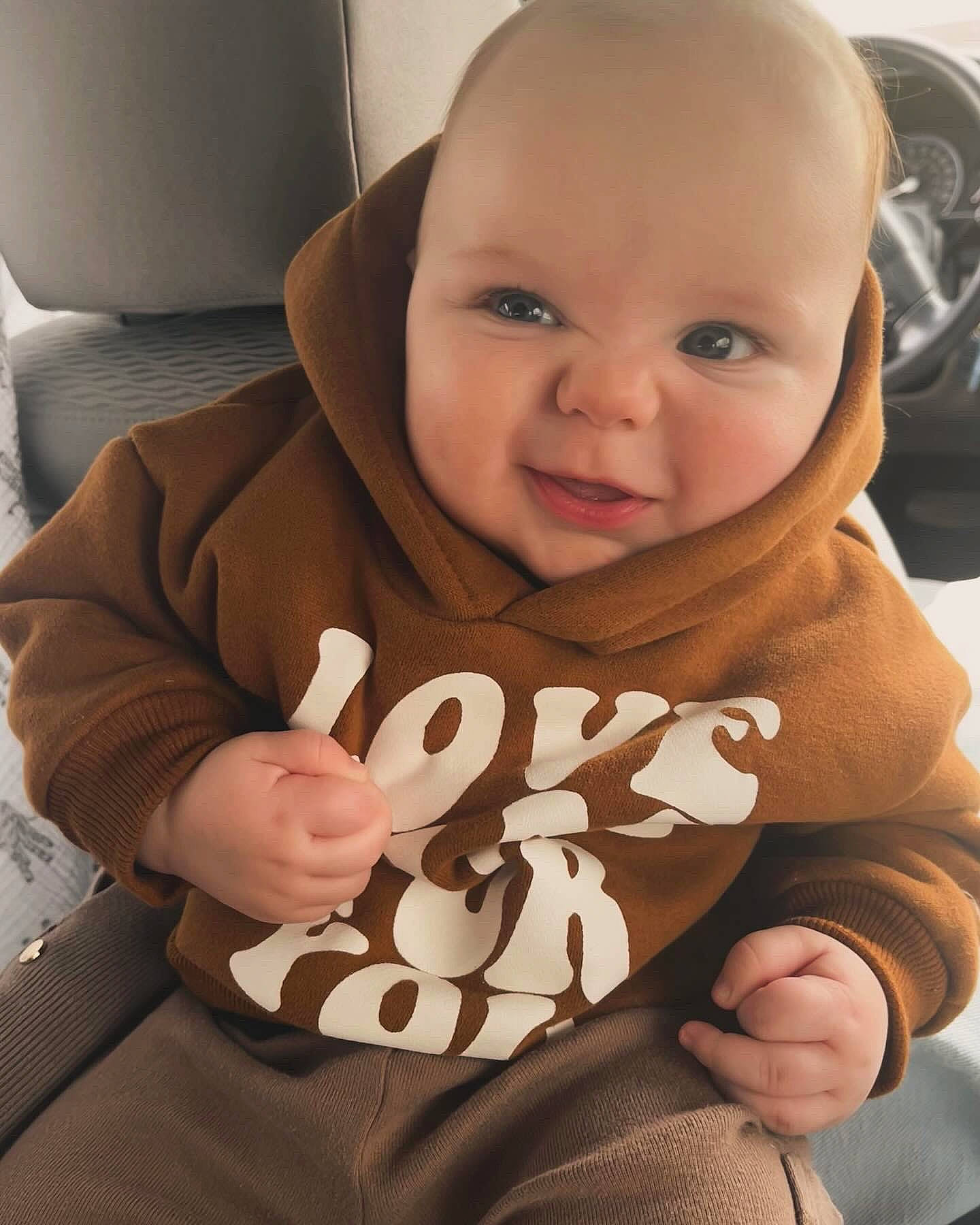 Maxwell is registered to the contest to win money with this photo: baby, baby_toddler_clothing, brown, cheek, comfort, cool, eye, finger, gesture, happy, head, mouth, nail, nose, person, sitting, skin, sleeve, smile, thumb