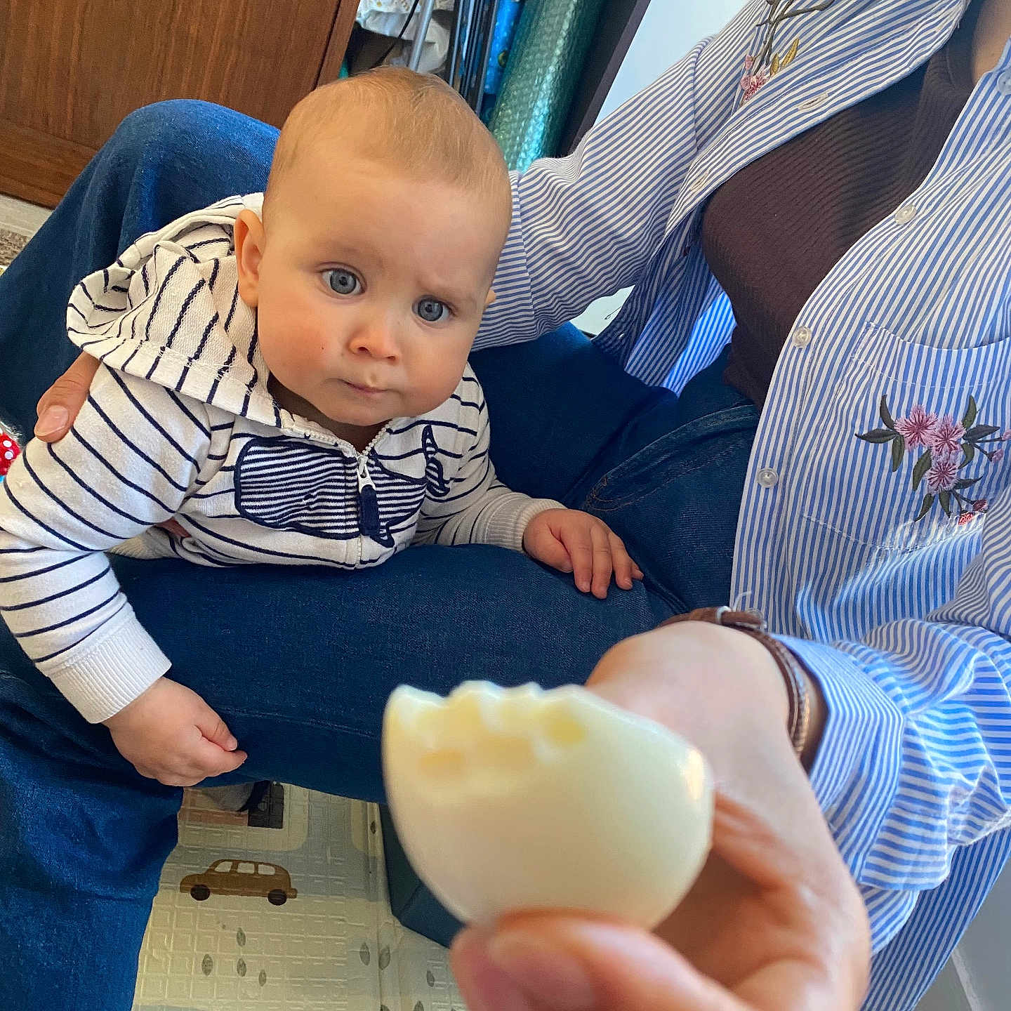 Daniel participe au concours pour gagner de l'argent avec cette photo : baby, child, woman, striped_clothing, blue_eyes, indoor, floor_mat, boiled_egg, hand, curious, sitting, person, casual_clothing, jeans, hoodie, pattern, toy_storage, home, portrait, expression