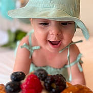 Michelle joined the competition — help win amazing prizes! baby, child, hat, green, food, fruit, berry, raspberry, blackberry, blueberry, tart, dessert, smile, happy, cute, closeup, indoor, face, appetite, delicious