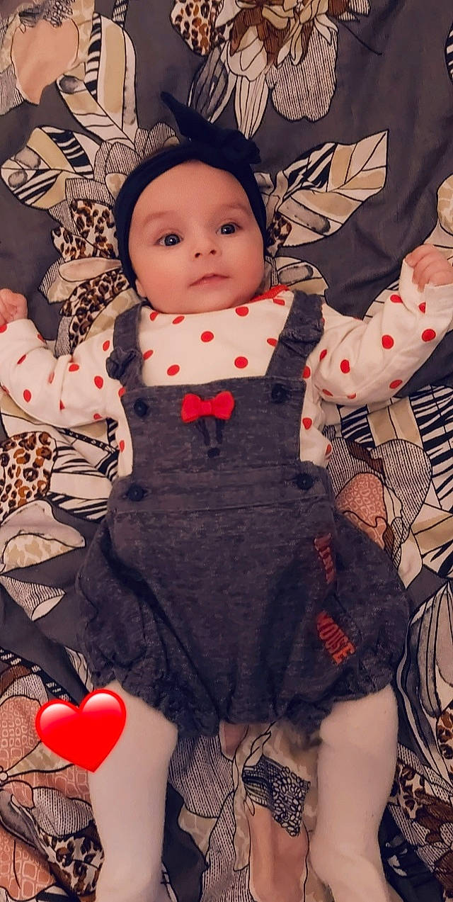 Inès participe au concours pour gagner de l'argent avec cette photo : arm, baby_toddler_clothing, black, black_hair, cheek, doll, dress, eye, hand, head, headwear, lip, pattern, person, pink, red, skin, sleeve, textile, toddler