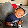 baby, child, toddler, smiling, sitting, couch, sofa, portrait, indoor, home, face, person, clothing, socks, shorts, shirt, furniture, happy, cozy, photograph