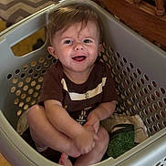 Waylon joined the competition — help win amazing prizes! baby, child, laundry_basket, smiling, drool, brown_shirt, indoor, wooden_furniture, carpet, clothing, cute, happy, person, sitting, household, playful, infant, face, tongue_out, casual