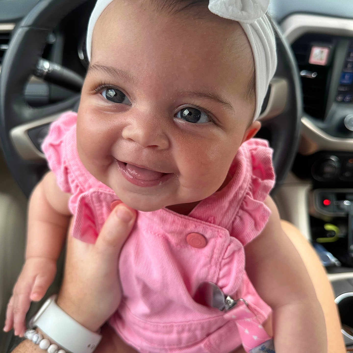 Naomi joined the competition — help win amazing prizes! baby, bright, car_interior, child, closeup, cute, dashboard, face, hand, headband, holding, human, infant, joyful, person, pink_clothing, portrait, seat, smiling, steering_wheel