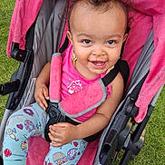 Aubriona joined the competition — help win amazing prizes! baby, child, infant, smiling, happy, portrait, stroller, pink, outdoor, grass, seated, harness, clothing, leggings, patterned_clothing, curly_hair, face, eyes, playful, photography