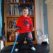 Bentley joined the competition — help win amazing prizes! child, toddler, spiderman_outfit, red_clothing, black_pants, blue_toy, toy_stick, smiling, indoor, wooden_shelf, books, potty_chair, floor, household_items, copper_pot, face, person, white_socks, short_hair, playful